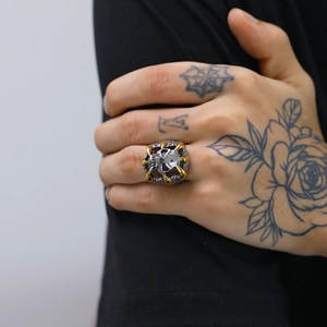 Macro shot of punk rock skull ring with gold eagle claws and silver oxidized metal finish