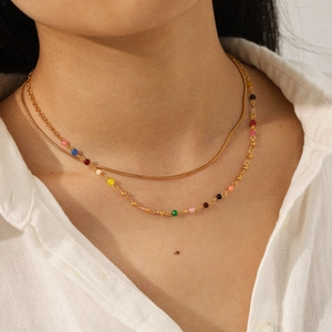 Close-up of a double-layered gold snake chain necklace with colorful beads on a model
