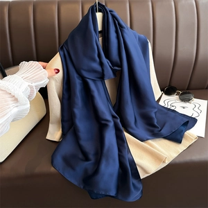Close-up of a deep blue silk-like scarf elegantly draped on a beige outfit over a brown sofa