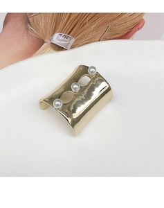 Detailed shot of a gold-plated metal U-shaped cuff bangle featuring three white pearls