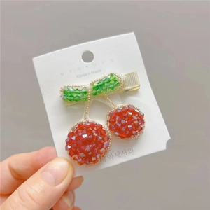 Detailed close-up of handmade beaded cherry hair clip with red sequins on white card