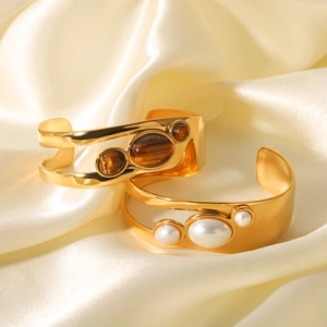 Macro shot of gold cutout open bangles set with natural tiger eye stone and pearls