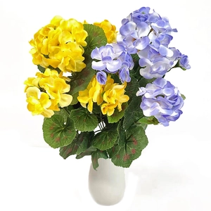 Detailed view of artificial yellow and purple geraniums in a white ceramic vase