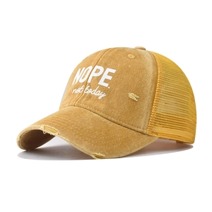 Detail of vintage yellow trucker hat featuring breathable mesh and NOPE embroidery