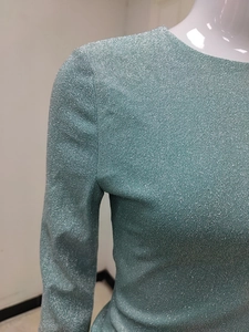 Detail of light blue metallic knit fabric on a long sleeve dress with shimmering texture
