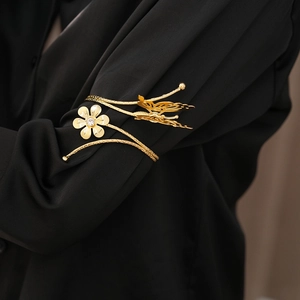 Detail of a golden arm cuff with butterfly and flower motifs on a black shirt sleeve