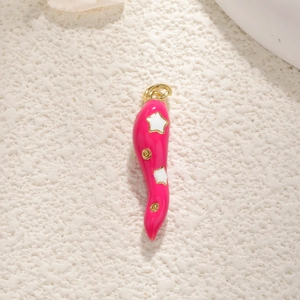Macro shot of a pink enamel chili pepper pendant with gold hardware and white star details