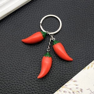 Detail of red resin chili pepper pendants on a durable metal keychain for bags
