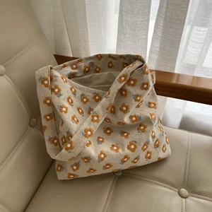 Detailed close-up of yellow flower embroidery and simple wish label on canvas tote bag