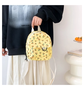 Detail of yellow corduroy mini backpack featuring red cherry prints and fabric straps