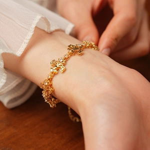 Gros plan d'un bracelet vintage doré fleur de lys orné de pierres de zircone brillantes