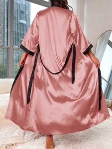 Rear view of pink satin robe with black trim and silk texture in modern bedroom setting