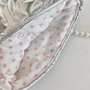 Dettaglio borsa argento con fiocco, bordo in pizzo e fodera a pois rosa chic