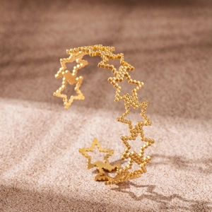 Polished 18K gold plated heart and star C-shape bangle on a warm sand background