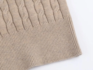Macro detail of beige cable knit sweater texture with ribbed hemline finish