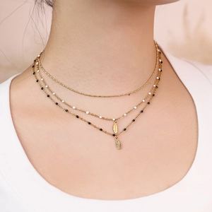 Three-layer gold necklace with feather pendants and decorative beads on model