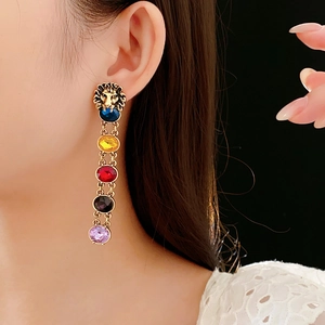 Gros plan de boucles d'oreilles tête de lion vintage avec strass colorés et longs pompons
