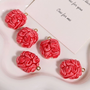 Macro shot of five red resin brain charms with gold hanging loops on a display tray
