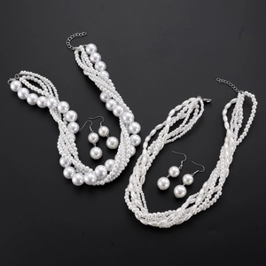 Flat lay of vintage multi-layer white pearl necklaces and matching earrings on black background