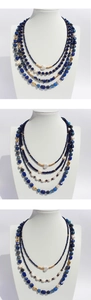Close-up of layered blue lapis lazuli beads and baroque pearls on a gold necklace