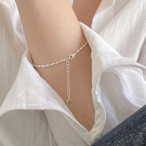 Close-up of minimalist S925 sterling silver beaded bracelet with heart charm on a wrist