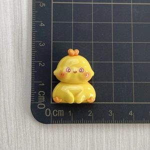 Close-up of small yellow resin chicken figurine on grid cutting mat for DIY crafts