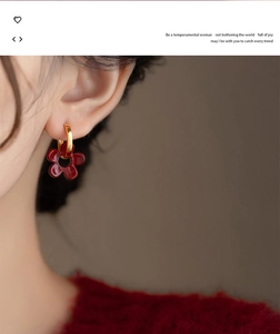 Vue détaillée de boucles d'oreilles fleur rouge rétro avec anneau doré sur l'oreille