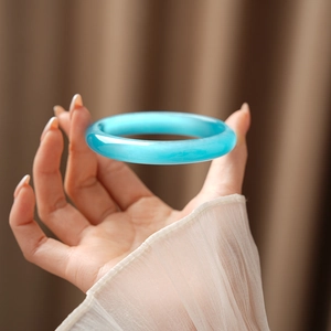 Detailed close-up of icy blue cat eye stone bangle with polished round design on wrist