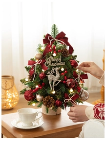 Detail of decorated desktop Christmas tree with red bows, pine cones and LED lights