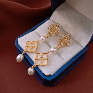 Boucles d'oreilles trèfles dorées avec zircons et perles dans un écrin de luxe