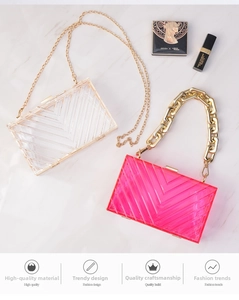 Flat lay of clear and neon pink acrylic evening bags with gold metal chain straps