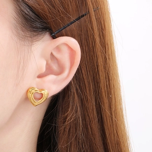 Close-up of a 18K gold-plated hollow heart stud earring worn by a model on white background