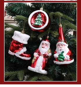 Detailed view of red and white glitter Santa Claus and boot ornaments on a tree branch
