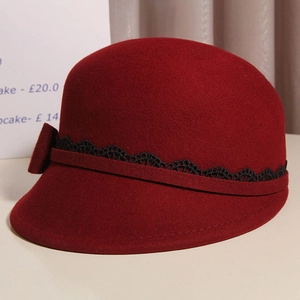 Detail of elegant burgundy wool felt cloche hat with black lace trim and bow accent