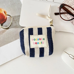 Detail of striped fabric makeup pouch with retro metal zipper and woven brand label