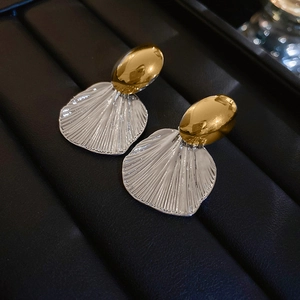 Vue macro de puces ovales dorées et boucles d'oreilles pendantes en éventail argent