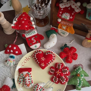 Detail of handmade wool felt Christmas ornaments with trees and gloves in a rustic box