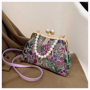 Details einer floralen Bügeltasche mit großem Perlenverschluss und Perlenkette
