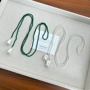 Detail of long beaded necklace featuring dark green spinel and baroque pearls in a tray