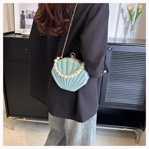 Detail of light blue shell crossbody bag featuring pearl handle and gold chain strap