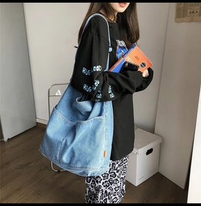 Detailed side view of large capacity light blue washed denim shoulder bag on model