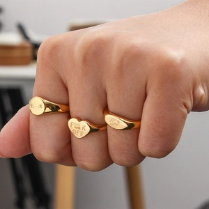 Close-up of gold rings with FUCK OFF engraving on model fist, street style jewelry set