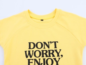 Detail of crew neck yellow cotton T-shirt featuring 'DON'T WORRY, ENJOY' black letter print