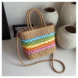 Detailed texture of handcrafted rainbow striped straw tote bag on a minimalist white desk