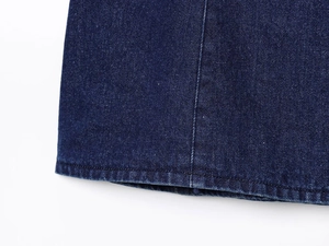 Détail du tissu denim bleu foncé avec coutures doubles précises sur l'ourlet du vêtement