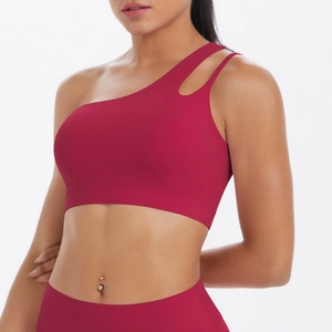 Detail of burgundy asymmetric one-shoulder sports bra with cutout strap and elastic fabric