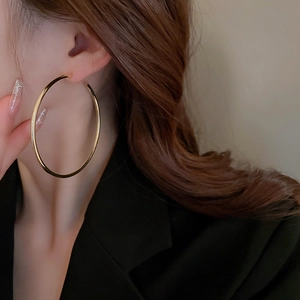 Close-up of oversized golden hoop earrings on a model showing smooth metallic finish