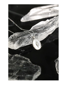 Macro shot of silver tulip necklace with white shell inlay on a crystal background