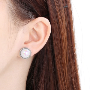 Close-up of elegant faux pearl stud earring with silver beaded border on model