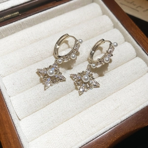Close-up of 18K gold-plated rhombus earring with a center pearl and zircon stones